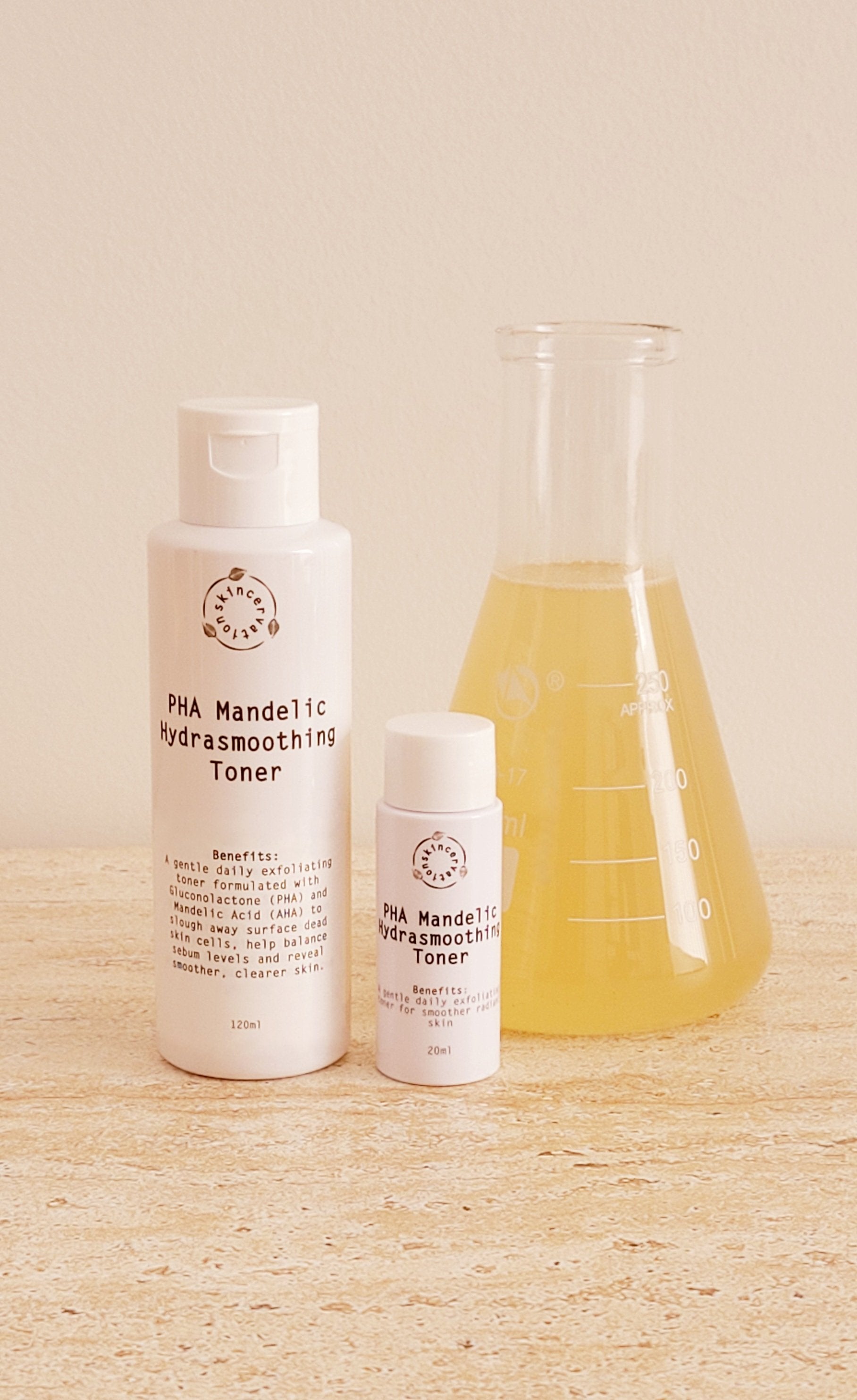 Skincervation pHA Mandelic AHA Hydrating and Smoothing Toner in two sizes 20ml and 50ml next to scientific beaker with  yellow liquid