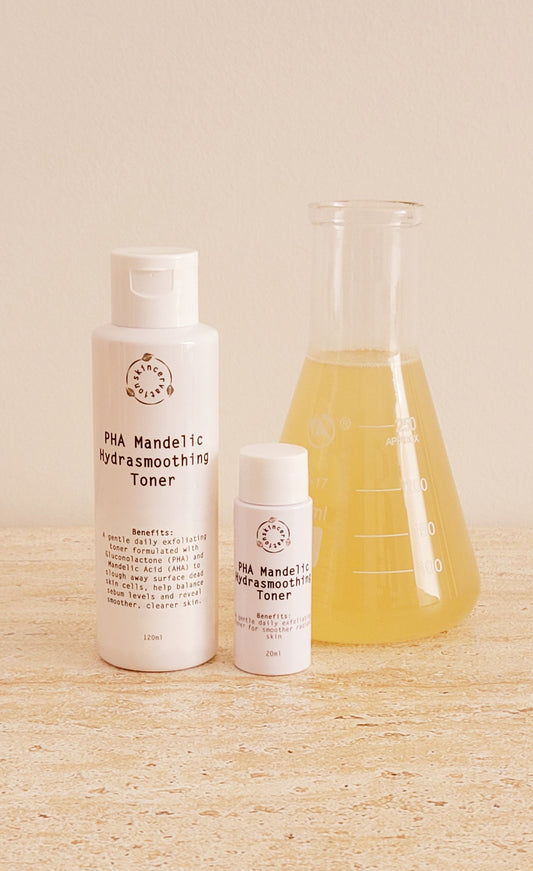 Skincervation pHA Mandelic AHA Hydrating and Smoothing Toner in two sizes 20ml and 50ml next to scientific beaker with  yellow liquid